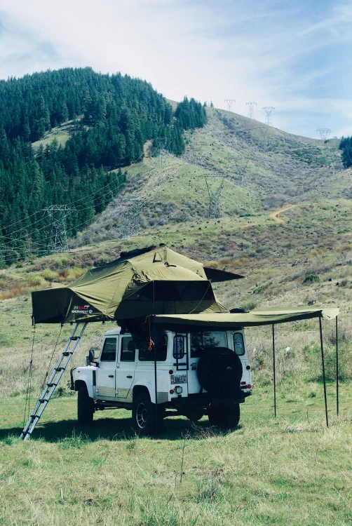 Front view of the Perentie 110 with rooftop tent and awning deployed, Mount Hood in the background