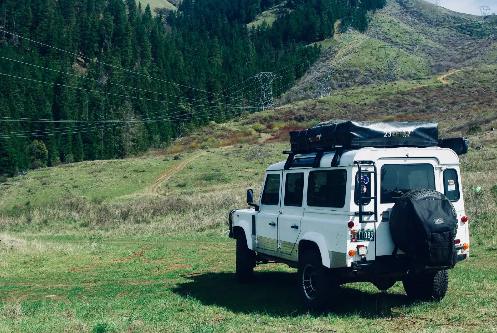 Rear three-quarter view of the Perentie 110 with rooftop tent stowed on a grassy trail